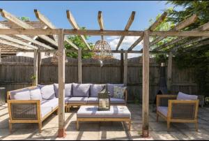 un patio con sofá y sillas bajo una pérgola en Cotswolds Lodge in Minster Lovell, en Minster Lovell