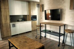 a kitchen with white cabinets and a table and stool at APARTAMENT Inspiracja in Mrągowo
