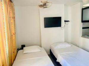 2 camas en una habitación con TV en la pared en Santa Marta Apartamentos - Brisas Marina, en Santa Marta