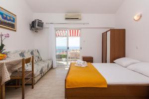 um quarto com uma cama, uma mesa e um sofá em Apartments Erceg em Makarska