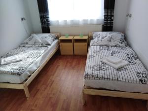 two beds in a room with wooden floors and a window at Arinza Apartman Vendégház in Mezőkövesd