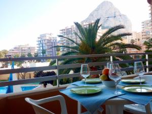 a table with wine glasses and a palm tree on a balcony at Voramar in Calpe