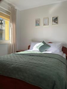 una camera da letto con letto con lenzuola verdi e finestra di Willa Mira 200 metrów od morza a Międzyzdroje