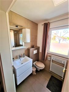 a bathroom with a sink and a toilet and a window at Apartment Villa Engel with Pool in Poreč