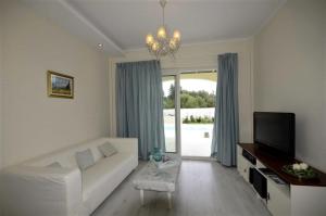 Villa Evanna في ليفكيمي: غرفة معيشة مع أريكة بيضاء وتلفزيون