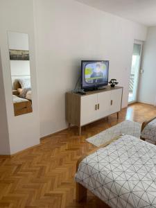 a living room with a tv on a cabinet at Apartmani Nedim in Dubrave Gornje