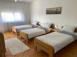 a room with three beds and a picture on the wall at Apartmani Nedim in Dubrave Gornje