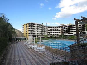 una piscina con tavoli e sedie bianche ed edifici di Casa de campo em resort com banheiras água termal a Santo Amaro da Imperatriz