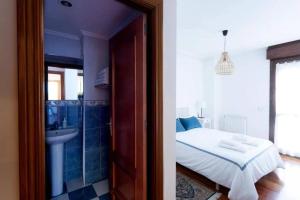 ein Schlafzimmer mit einem Bett und ein Badezimmer mit einem Waschbecken in der Unterkunft EL BALCÓN DE CAMPO LOS PATOS in Oviedo