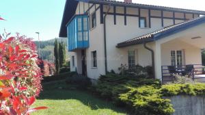 ein weißes Haus mit blauen Fenstern und einem Garten in der Unterkunft URDINETXE in Luyando