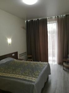 a bedroom with a bed and a large window at Апартаменты на Соборном с видом на парк in Zaporozhye