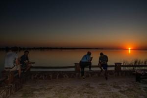 a group of people sitting on a dock watching the sunset at Arandu ecolodge in Colonia Carlos Pellegrini