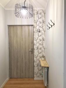 korytarz z drewnianymi drzwiami i żyrandolem w obiekcie Pastelove mieszkanie przy centrum - bezkontaktowo w Bielsku Białej