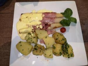 un plato blanco de comida con patatas y queso en Hotel Radevormwald, en Radevormwald
