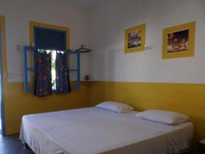 una camera con un letto bianco e una finestra di Pousada Aldeia do Sossego a Santa Cruz Cabrália