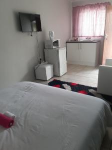 a bedroom with a white bed and a kitchen at Ruros Guest House in Kempton Park