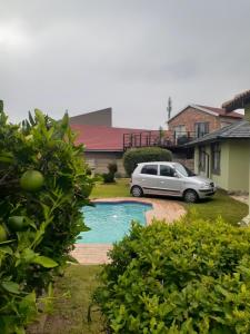 a car parked in front of a house with a pool at Ruros Guest House in Kempton Park