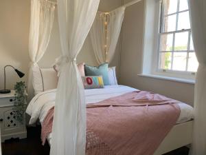 Un dormitorio con una cama con dosel y una ventana. en Warders Cottage: Iconic Cottage in the Heart of Freo, en Fremantle