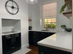 a kitchen with black and white counters and a window at Warders Cottage: Iconic Cottage in the Heart of Freo in Fremantle