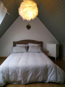 a bedroom with a large white bed with a chandelier at TI-ARMOR in Louannec