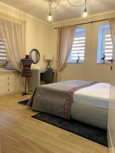 Schlafzimmer mit einem Bett, einem Schreibtisch und Fenstern in der Unterkunft Diva Garden Apartment in Plowdiw