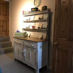 a dresser with a clock on a wall next to a door at No.18 Holmfirth in Holmfirth