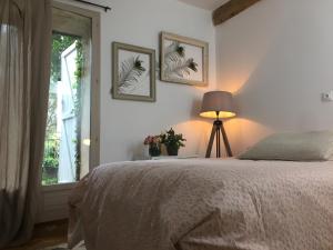 ein Schlafzimmer mit einem Bett, einem Fenster und einer Lampe in der Unterkunft Domaine Sesquier Mas d'exception Jasmin in Mèze