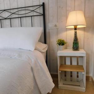 1 dormitorio con cama y mesita de noche con lámpara en Apartamento La Placeta, en Monroyo