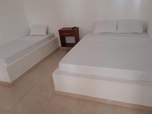 a white bedroom with two beds and a night stand at Hotel Central Fusa in Fusagasuga