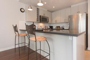 a kitchen with two bar stools and a stainless steel refrigerator at Lower Lonsdale Aprtment in North Vancouver