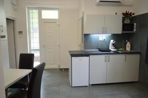 a kitchen with white cabinets and a black counter top at Belvárosi Apartman in Pécs