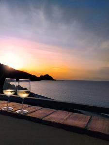due bicchieri di vino seduti su un tavolo con il tramonto di Sea Sound House a SantʼAmbrogio