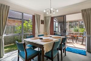 a dining room with a table and chairs and windows at Fantails Roost - Bowentown Holiday Home in Waihi Beach