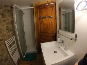 een badkamer met een wastafel en een houten deur bij Les Gites Du Mazel in champis