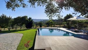 una piscina en un patio con sombrilla en Quinta das Regueiras, en Viseu