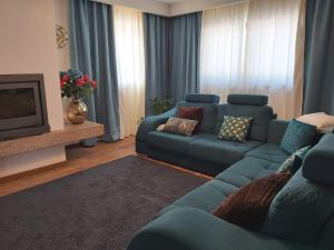 a living room with a blue couch and a television at Quinta das Regueiras in Viseu