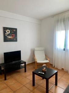 a living room with a tv and a chair and a table at APARTAMENTO ALAMILLO Alto in Chinchón
