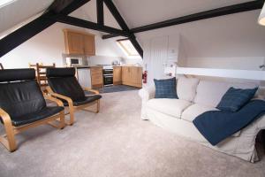 a living room with a white couch and two chairs at Long Byres Holiday Cottages in Brampton