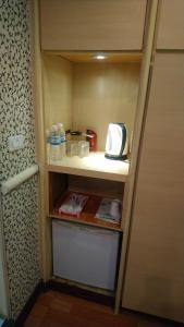 a small kitchen with a microwave on a shelf at Yadu Hotel in Bade