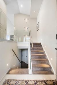a staircase in a house with white walls and wooden floors at Luxury Lakeview Vista Apartment in Wanaka