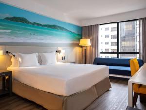 a hotel room with a large bed and a large window at Novotel Florianopolis in Florianópolis