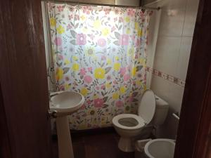baño con aseo y cortina de ducha con flores en Casas Las Coloradas, en Piriápolis