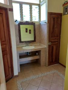 een badkamer met een wastafel en een spiegel bij Cabina Rancho la Merced in Uvita