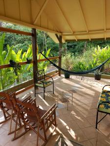 a porch with chairs and a hammock on it at Cabina Rancho la Merced in Uvita