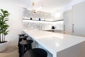 a kitchen with a white counter and stools at SandCastles Noosa in Noosa Heads