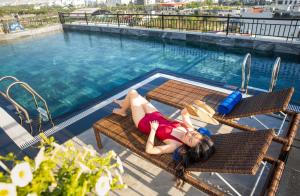 uma mulher deitada numa cadeira ao lado de uma piscina em Tan Phuong Nam Hotel & Apartment em Da Nang