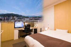 
a hotel room with a bed, tv and a desk at Spa Hotel Alpina Hida Takayama in Takayama
