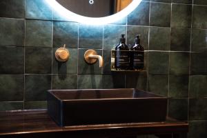 lavabo en el baño con 2 botellas de vino en la pared en The Intrepid Hotel en Wellington