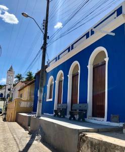 a blue building with two benches in a street at Pousada Ô de Casa in Piranhas