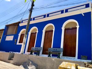 un edificio azul con dos bancos delante en Pousada Ô de Casa en Piranhas